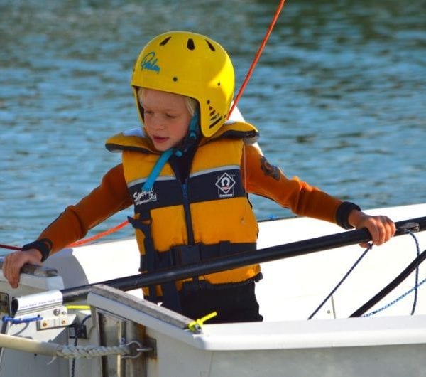 A young boy holding the stick of a dinghy
