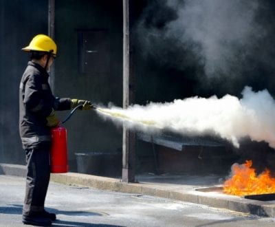 A student using a fire extinguisher on open flames