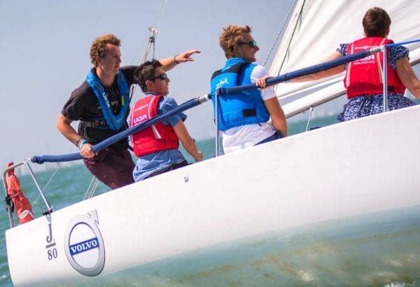A UKSA trained instructor on a yacht giving advice to trainee sailors.