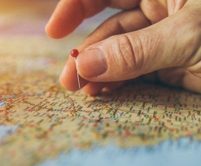 Hand pin pointing a location on a world map