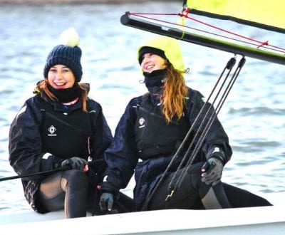 Two girls smiling and laughing onboard a dinghy at UKSA
