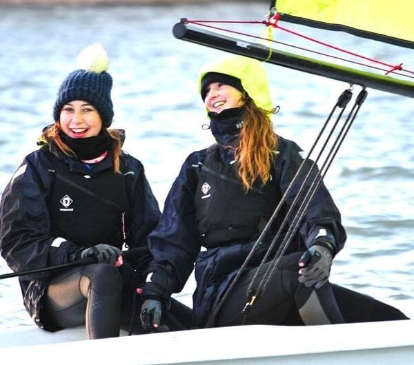 Two girls smiling and laughing onboard a dinghy at UKSA