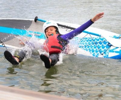 A young person falling off his paddleboard into the water