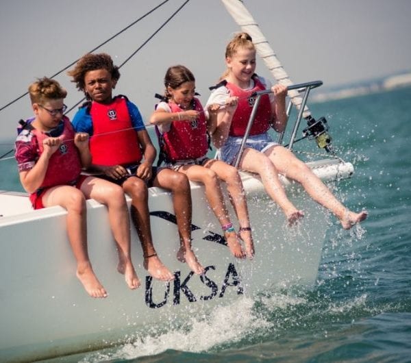 Young children sitting on the bow of a yacht enjoying the waves