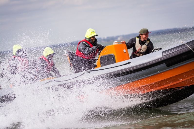Group riding orange speedboat through crashing waves
