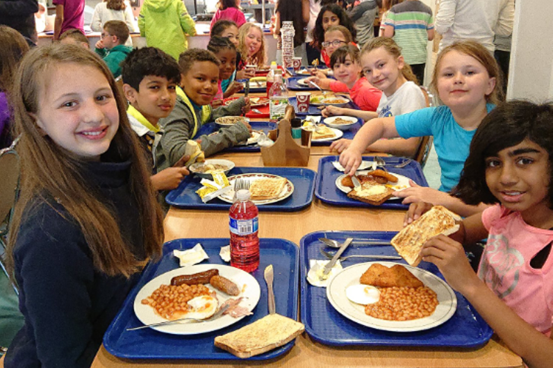 Young school children eating breakfast in the canteen