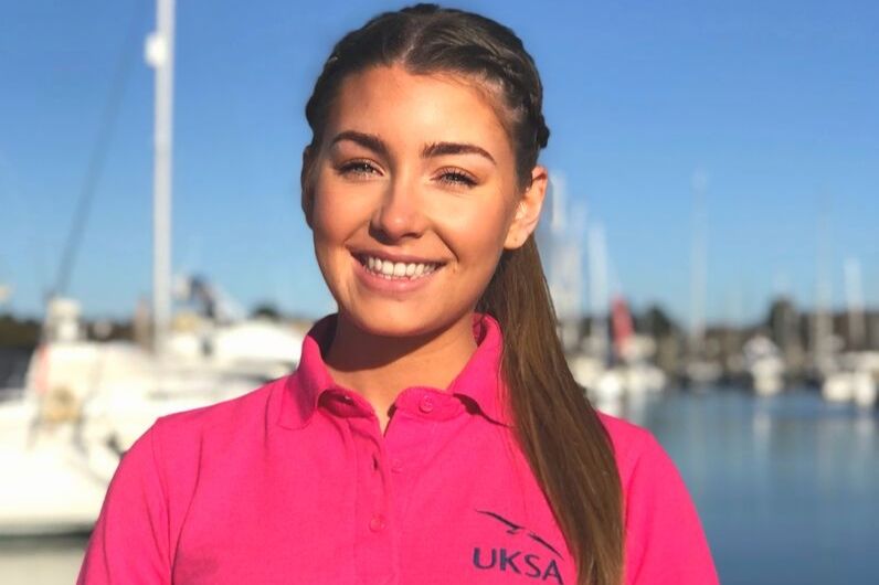 A young girl wearing a pink UKSA polo shirt smiling at the cameras