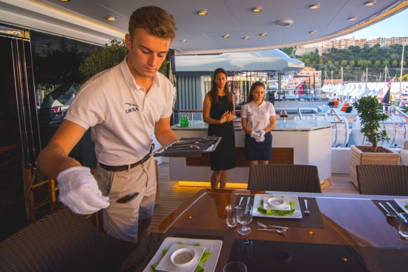 A male Hospitality student setting a table onboard a Superyacht