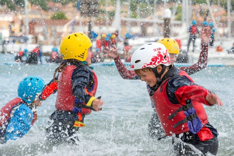 children wearing life jacket splashing in water