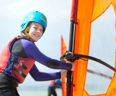 A female student holding up her Windsurf sail