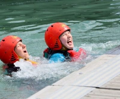 Two students in the water wearing red helmets