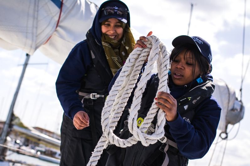 Two female yachting students holding rope