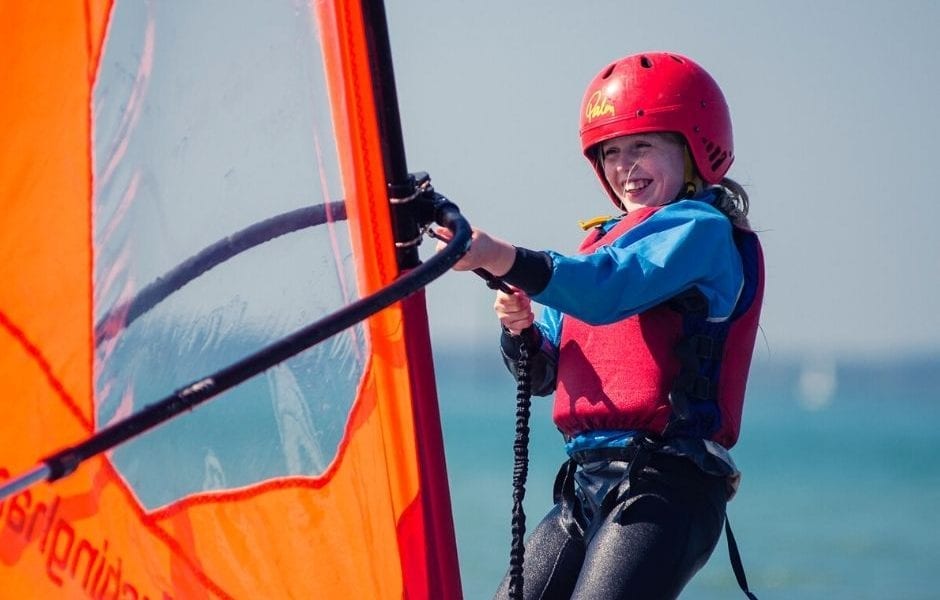 A young girl smiling while wind surfing