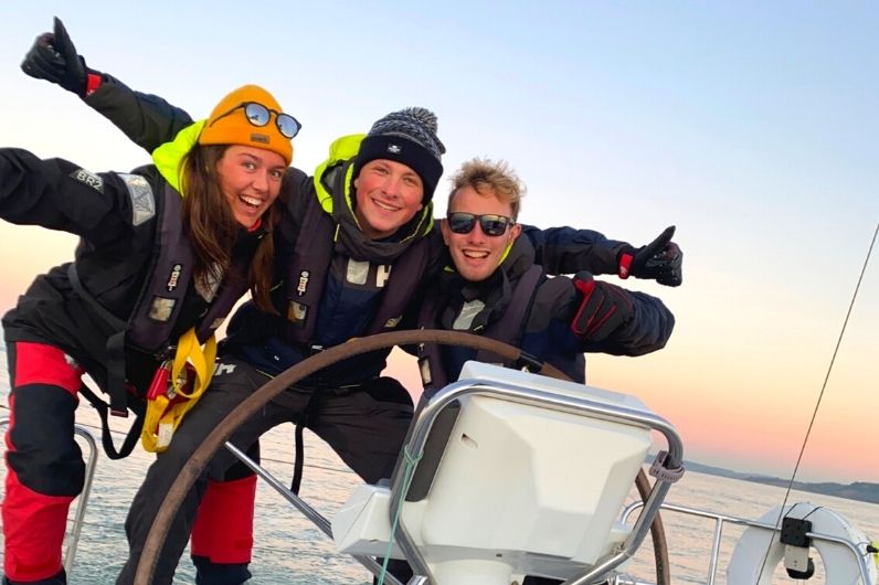 A group photo of three students onboard a yacht