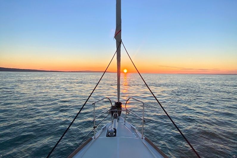 The bow of a yacht with the sunset in the distance